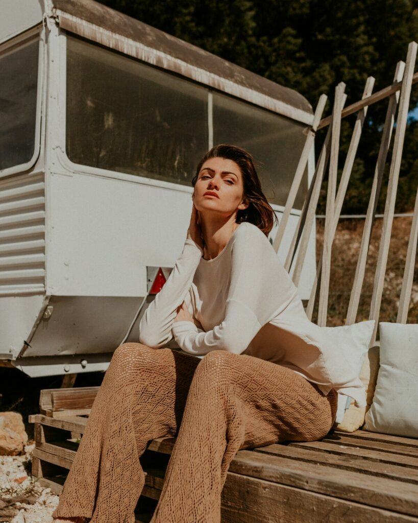 Marine Debut assise en tenue beige avec un pantalon marron lors d’un shooting